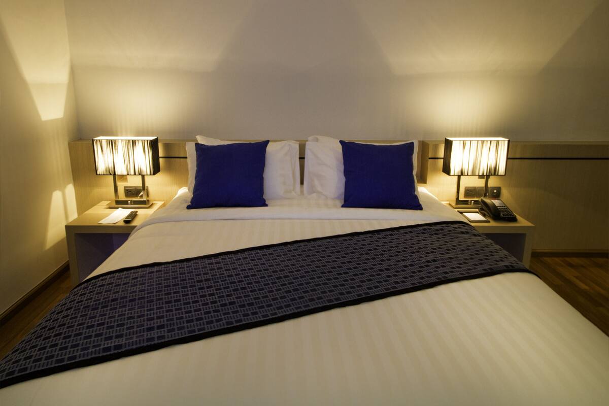 A hotel room with a large bed, two bedside tables with lamps, and a nightstand with a telephone.