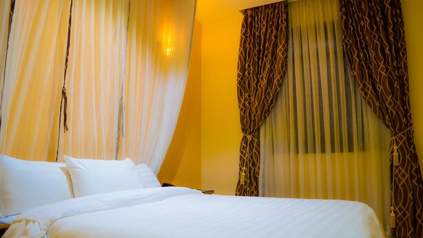 Une chambre d’hôtel avec un grand lit, du linge de lit blanc et des rideaux à motifs géométriques.