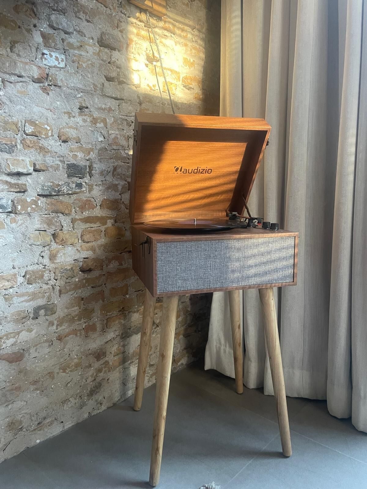 A wooden music player with the brand 'Audizio' on a stand with wooden legs.