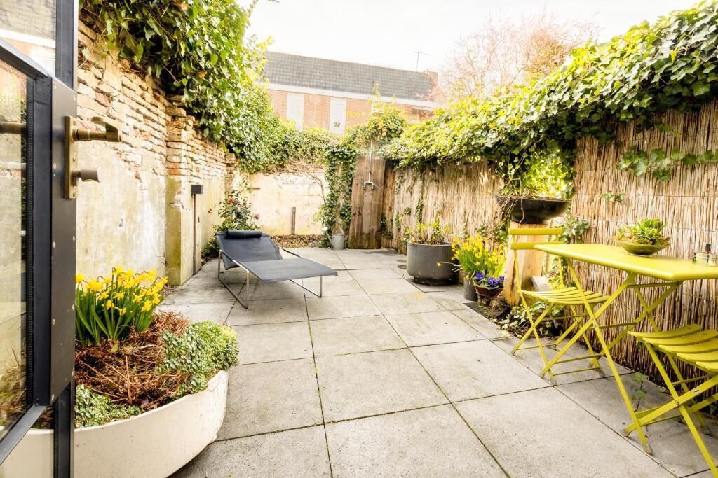 A patio with a seating area, a table, and potted plants.