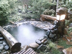 A hot spring surrounded by rocks and greenery.