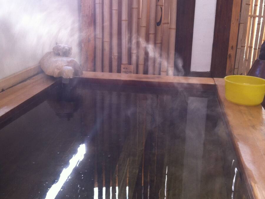 A traditional Japanese onsen with a wooden platform and a bamboo wall.