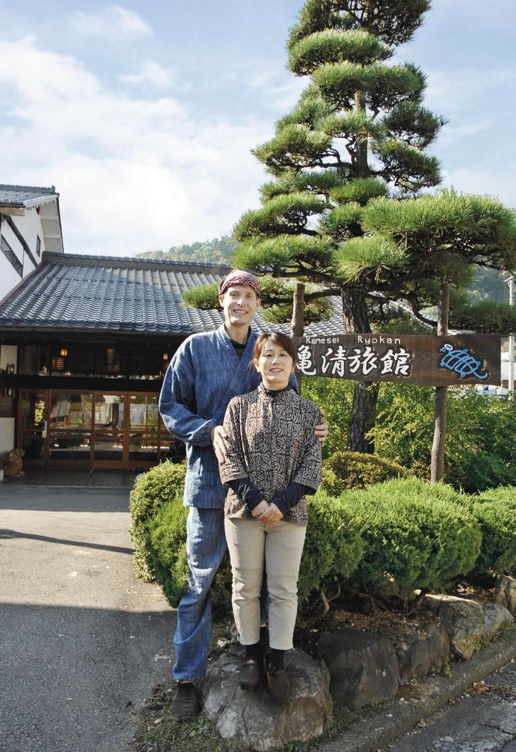 Un bâtiment traditionnel japonais, avec un toit recouvert de tuiles et une enseigne devant l’entrée.
