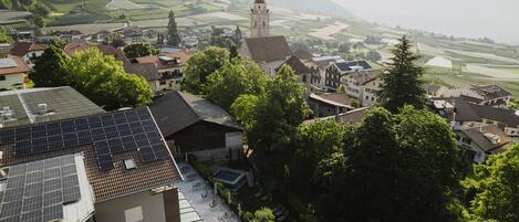 A village with traditional architecture, including a church with a prominent tower, surrounded by lush greenery and terraced fields.