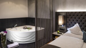 Une salle de bain moderne avec une baignoire sur pieds, un meuble-lavabo avec un miroir et une table de chevet avec une lampe.
