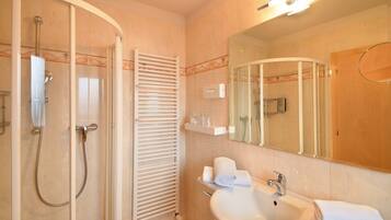 A modern bathroom with a glass-enclosed shower, a white sink, and a large mirror.