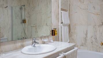 A bathroom with a marble sink, a glass-enclosed shower, and a white bathtub.