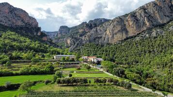 A hotel nestled in a valley with terraced fields, surrounded by mountains.