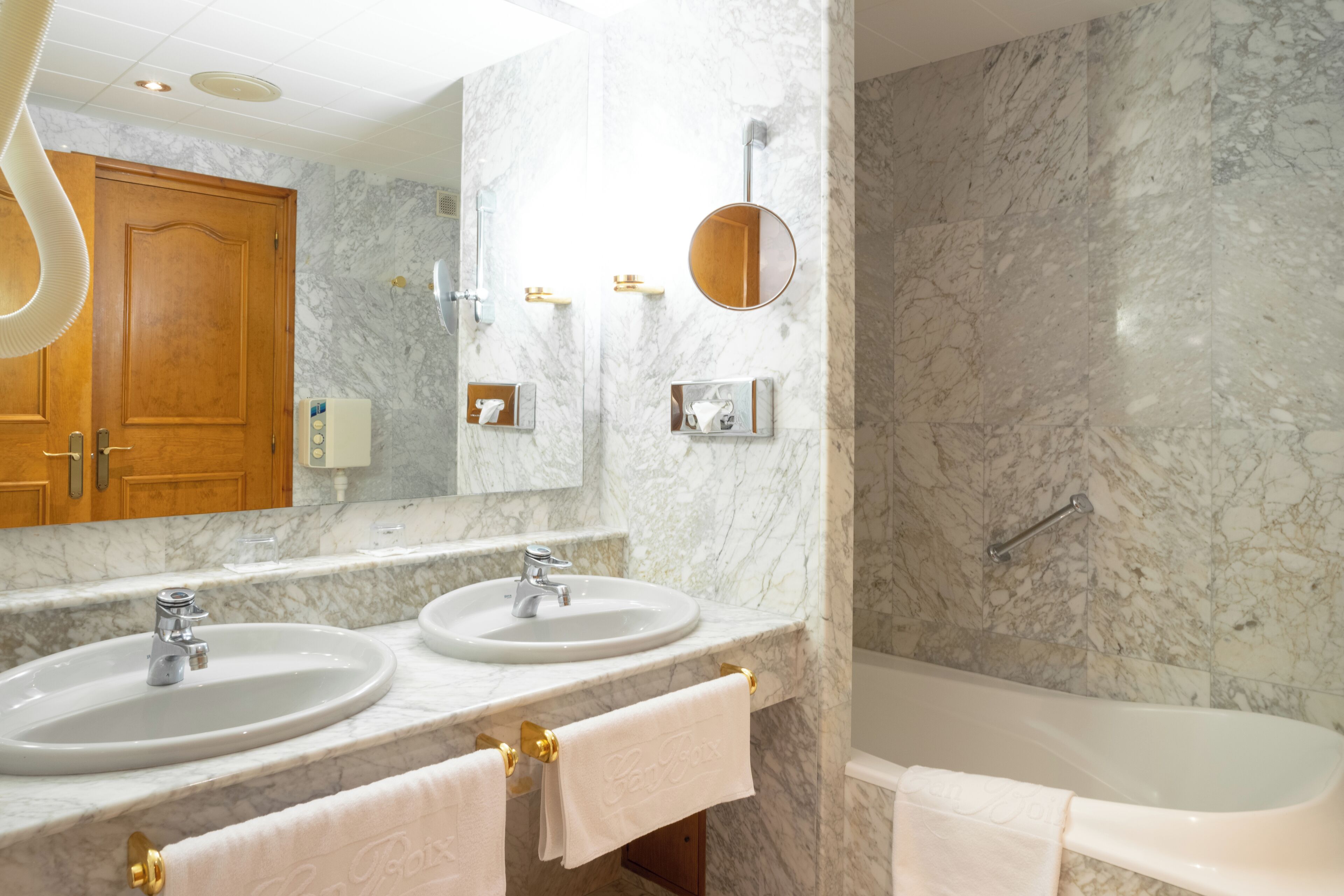 A bathroom with two sinks, a mirror, a towel rack, and a bathtub.