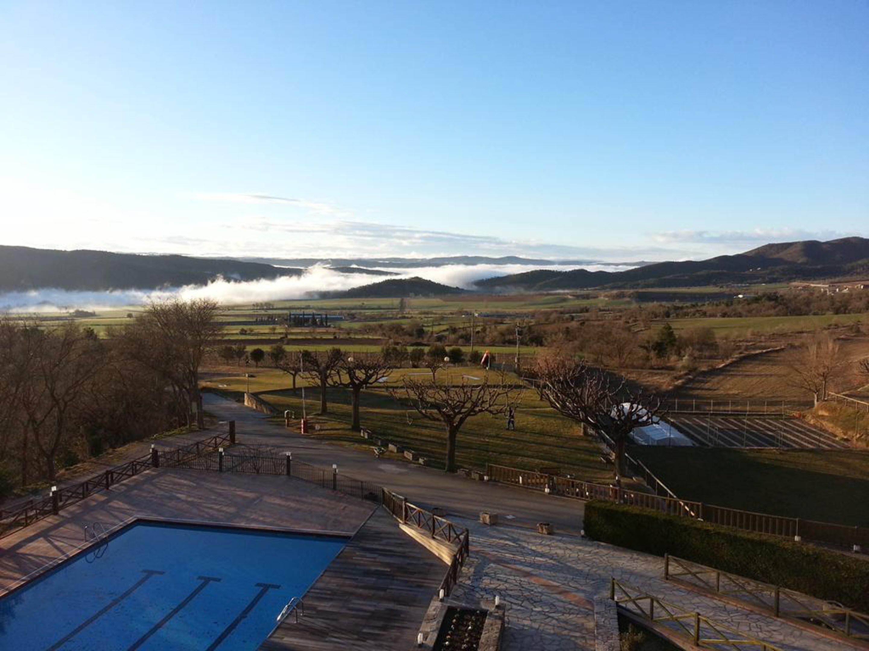 A swimming pool area with a view of a valley and mountains.
