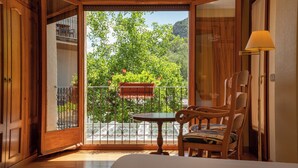 Una habitación con balcón, una silla de madera, una mesita y una lámpara.