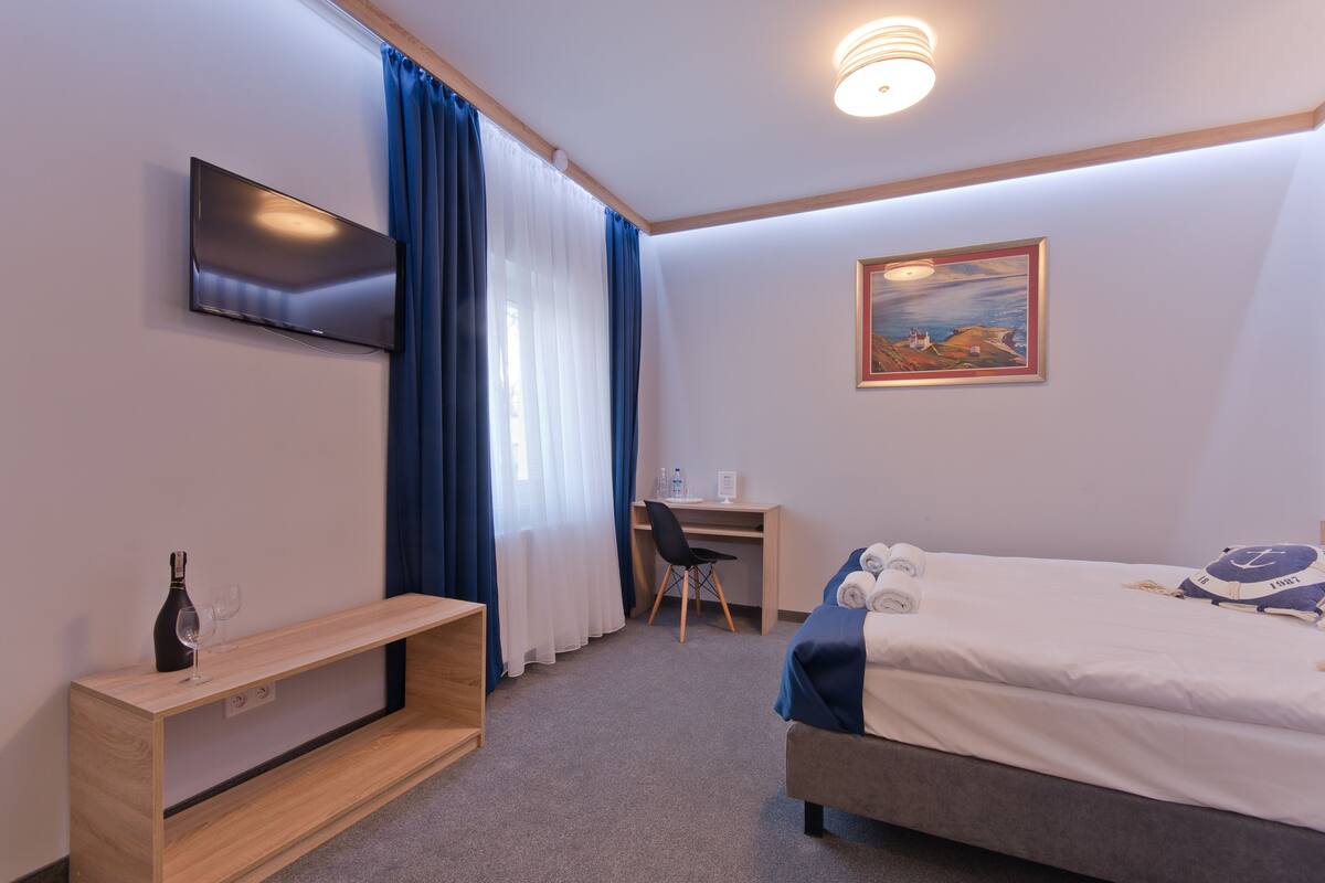 Habitación de hotel con cama, escritorio, televisor y un cuadro en la pared.