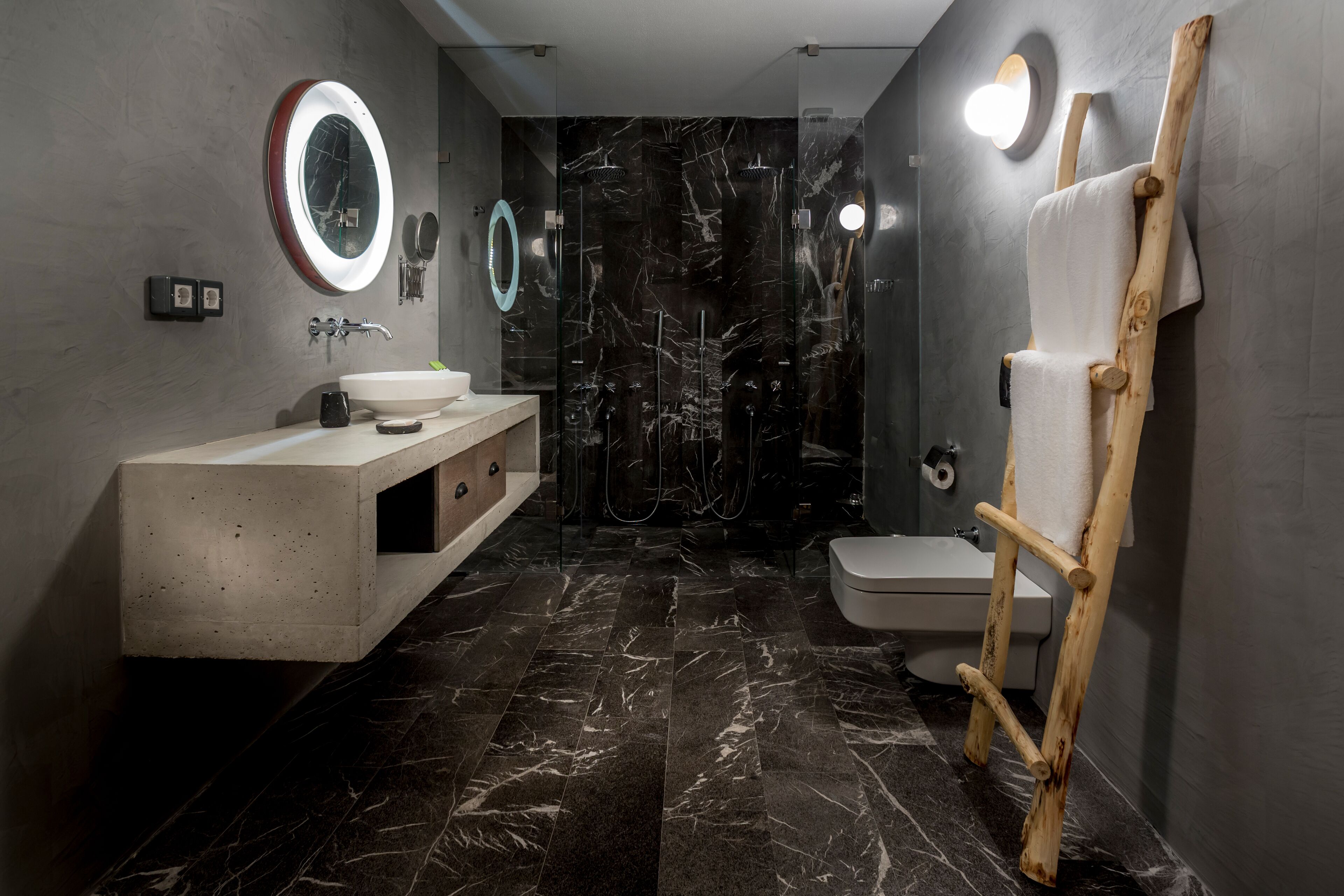 Un baño moderno con piso de mármol, una escalera de madera, un lavamanos con espejo y un inodoro.