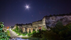A night view of a historic building with a starry sky, a well-lit pathway, and surrounding greenery. - Főnix Hotel Bükfürdő (Buk)
