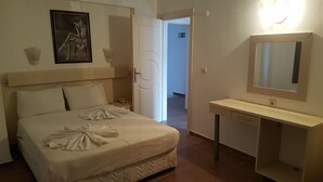 A hotel room with a bed, a bedside table, a mirror, and a door leading to another room. - Golden Star Otel (Marmaris)