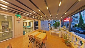 An indoor dining area with a table and chairs, a bench, and a potted plant. - Golden Star Otel (Marmaris)