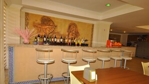 A bar area with a counter, bar stools, and a table with a box on it. - Golden Star Otel (Marmaris)