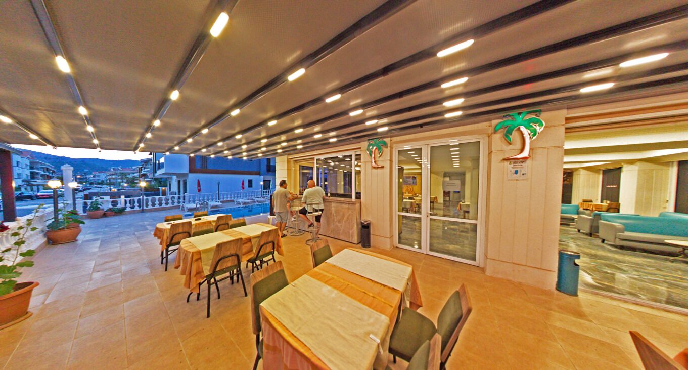 Comedor interior con mesas y sillas, vista a la piscina y una zona de bar.