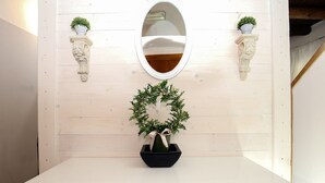 Una pared con un espejo, dos apliques con plantas y una guirnalda.