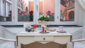 Una mesa de comedor blanca con un jarrón de flores, un vaso de jugo, un plato de comida y una taza.