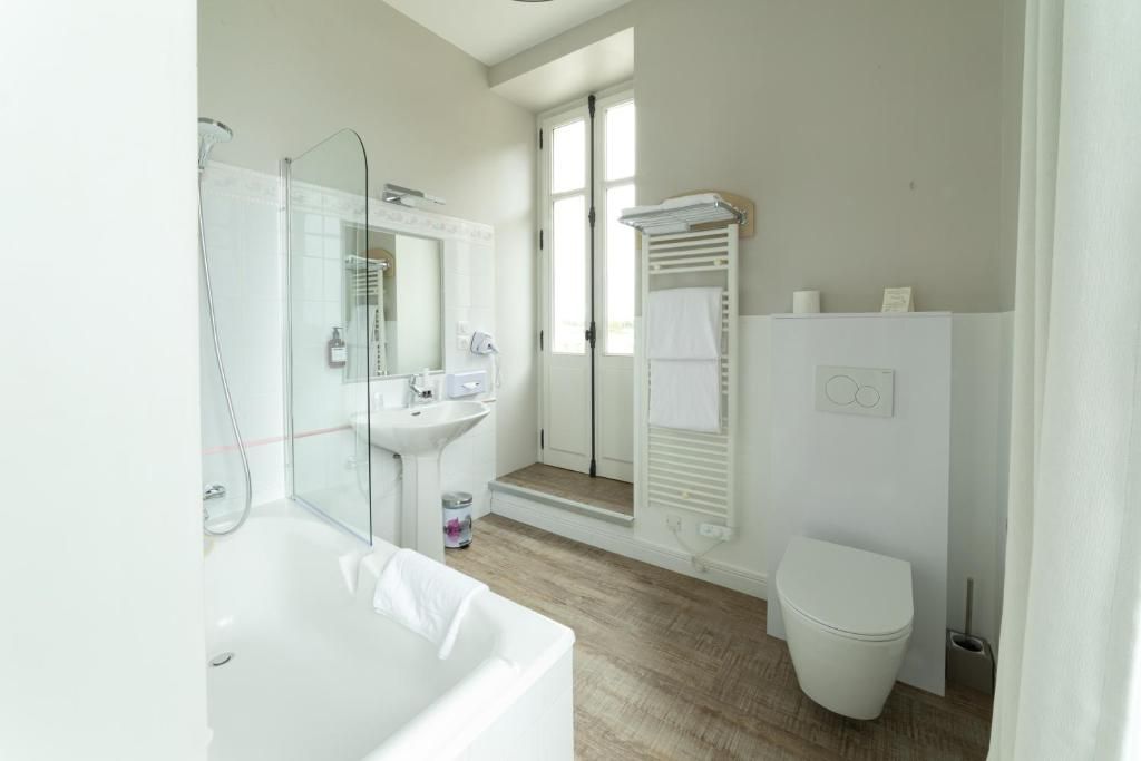 Ein modernes Badezimmer mit Badewanne, Dusche, Toilette und einem Fenster mit Tageslicht.