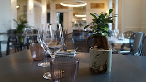A dining table with a potted plant, wine glasses, and a candle holder. - Château de la Gressière (La Bernerie-en-Retz)