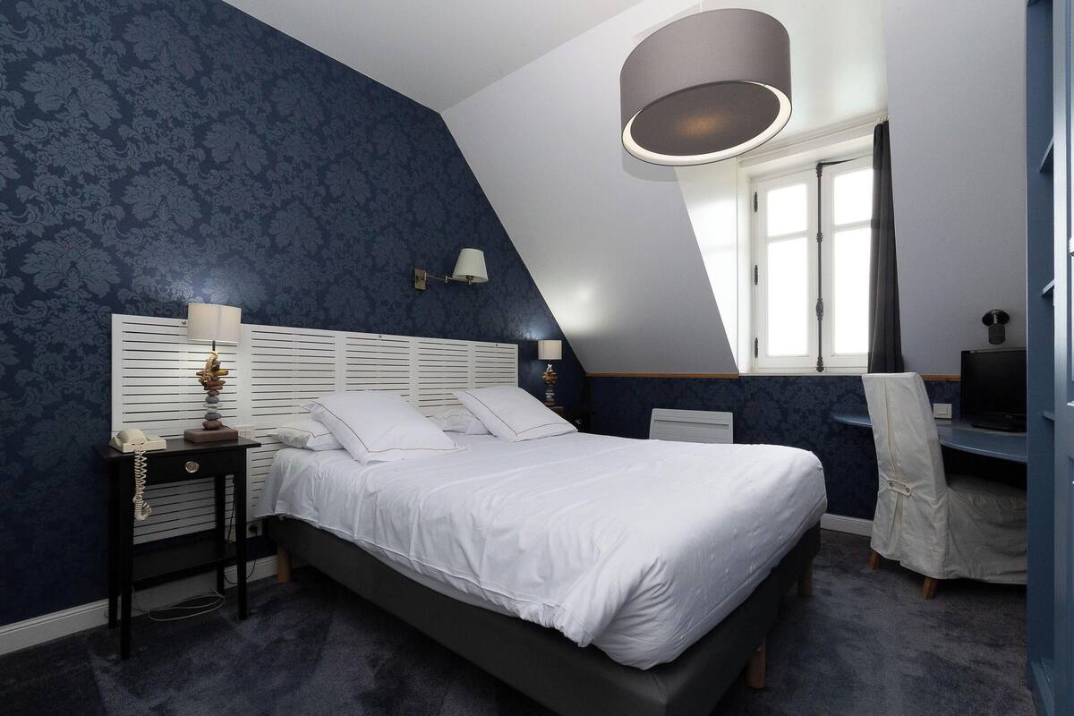 A bedroom with a bed, bedside tables, a desk, and a chair.