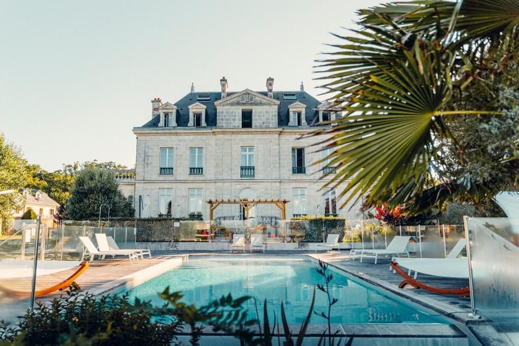 A large building with a swimming pool and lounge chairs.