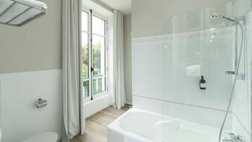 A modern bathroom with a bathtub, toilet, and a glass shower enclosure.