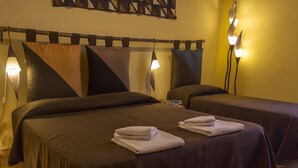 A hotel room with two beds, each with a pillow and a folded towel. There is a wall-mounted lamp between the beds. - Dimora dei Giganti (Naples)