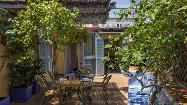 A patio with a table and chairs, surrounded by potted plants and a decorative wall. - Dimora dei Giganti (Naples)