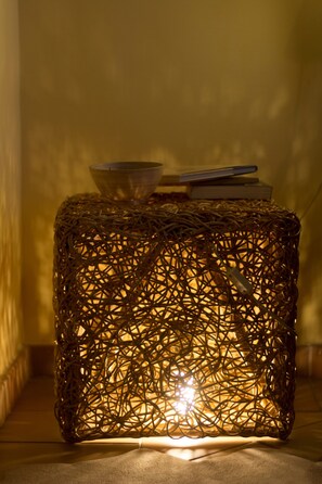 A woven, cylindrical lamp with a light source inside, placed on a flat surface. - Dimora dei Giganti (Naples)