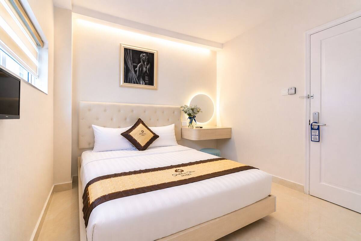 Een hotelkamer met een bed, een nachtkastje met spiegel, een tv aan de muur en een deur met een bordje.
