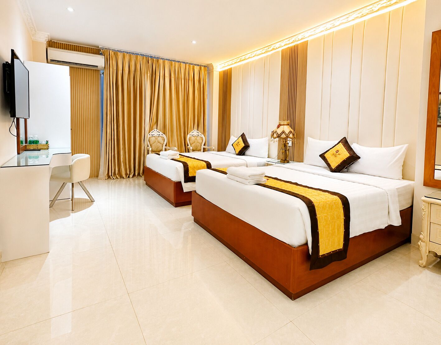 A hotel room with two beds, a desk, and a television.