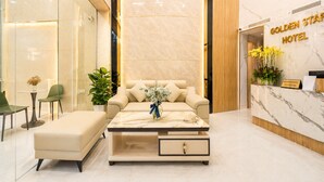A reception area with a marble reception desk, a sofa, a coffee table, and a receptionist sign. - Golden Star Hotel (Ho Chi Minh City)