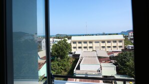 A view from a window overlooking a building with a flat roof and a large windowed facade. - Lien Thong Hotel (Phu Quoc)