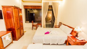 A hotel room with a bed, a desk with a lamp, a wardrobe, and a window with curtains. - Lien Thong Hotel (Phu Quoc)