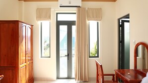 A room with a wooden wardrobe, a desk with a chair, a large mirror, and a sliding glass door leading to an outdoor area. - Lien Thong Hotel (Phu Quoc)