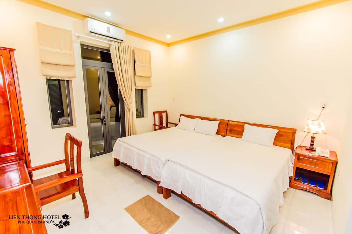 A hotel room with a large bed, wooden furniture, a desk, and a chair.