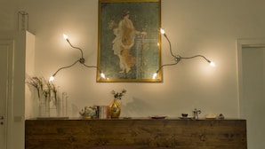A room with a wooden headboard, a wall-mounted painting, and a shelf with decorative items and books. - Diletto a Napoli B&B (Naples)