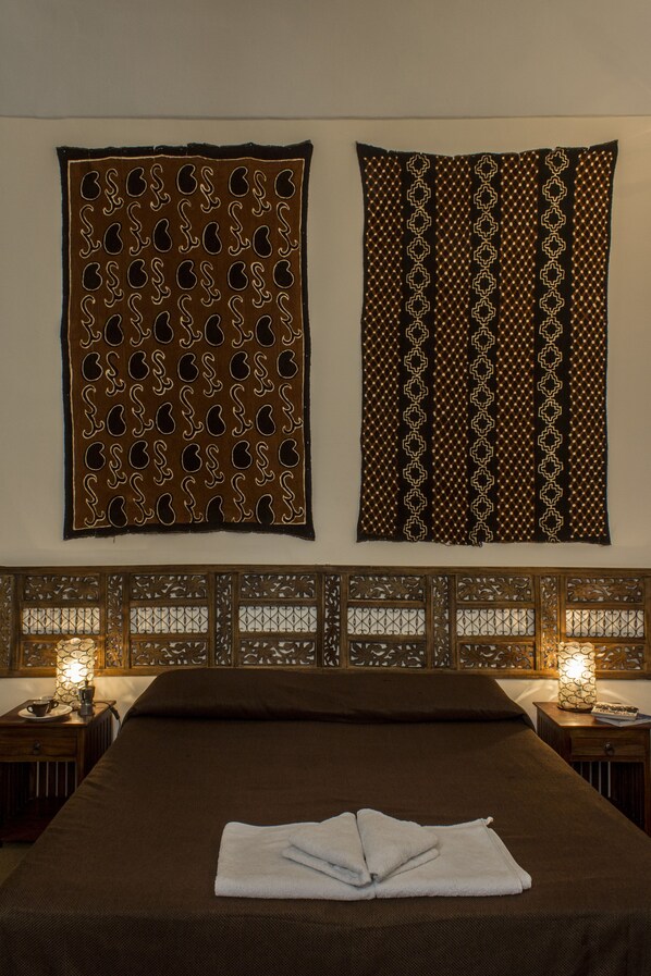 A neatly made bed with a folded towel, a decorative wall hanging, and two lit bedside lamps. - Diletto a Napoli B&B (Naples)