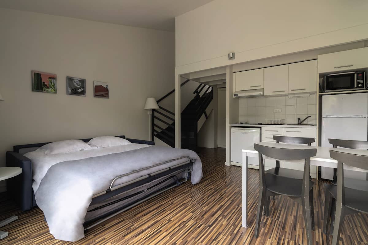 Ein modernes Zimmer mit einem Bett, einem kleinen Tisch und einer Küchenzeile.