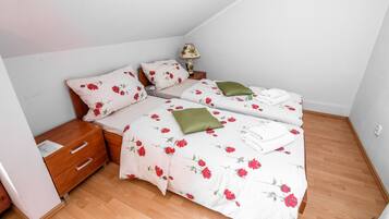 Une chambre avec deux lits, une table de chevet, une lampe et un plancher en bois.