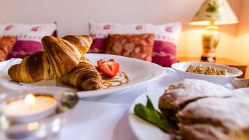 Een ontbijttafel met croissants, een aardbei en een kaars.