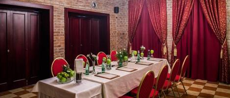 A dining area with a long table set for a meal, red chairs, and a chandelier.