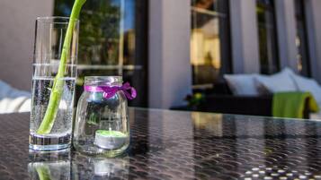 A glass vase with a single red tulip on a table in front of a building with a sign that reads "Cafe D'Italia".