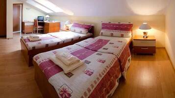 A bedroom with two beds, a desk, a chair, a computer, and a lamp.