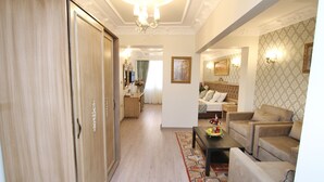 A spacious living area with a sofa set, a dining table, and a wooden wardrobe. - Apple Tree Hotel (Istanbul)