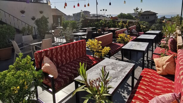 A rooftop terrace with outdoor seating, potted plants, and a clear view of the city skyline. - Apple Tree Hotel (Istanbul)