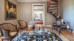 A spacious living room with a large painting, two wicker chairs, a glass coffee table, and a wooden staircase. - Quinta de São Tadeu (Sintra)